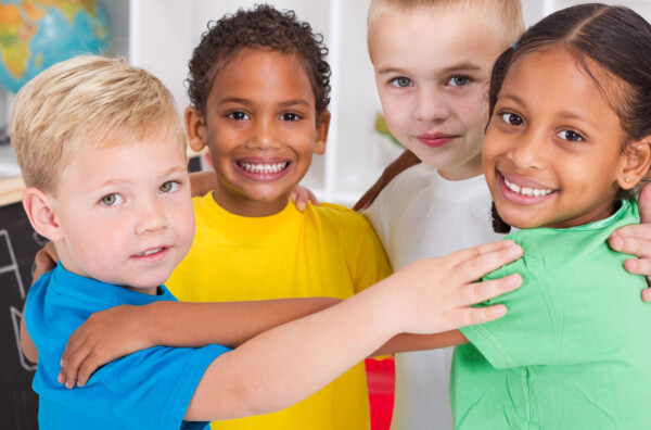 Multi-ethnic group of preschool students hugging and smiling
